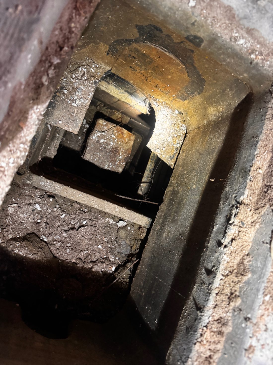 Looking down into a cast iron backwater valve with its rusted round flap stuck in the open position