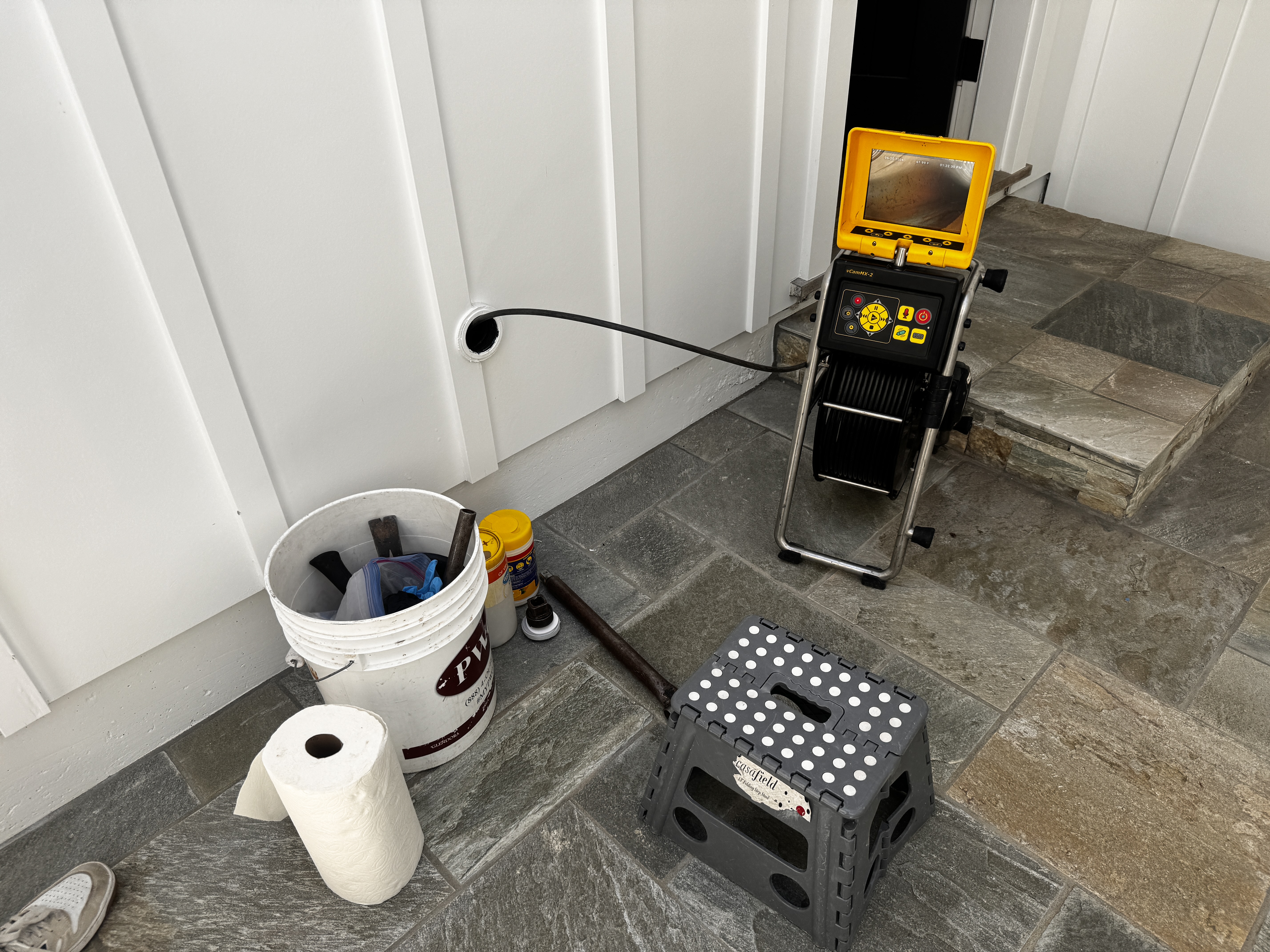 FlowPro technician running sewer camera through wall cleanout access point