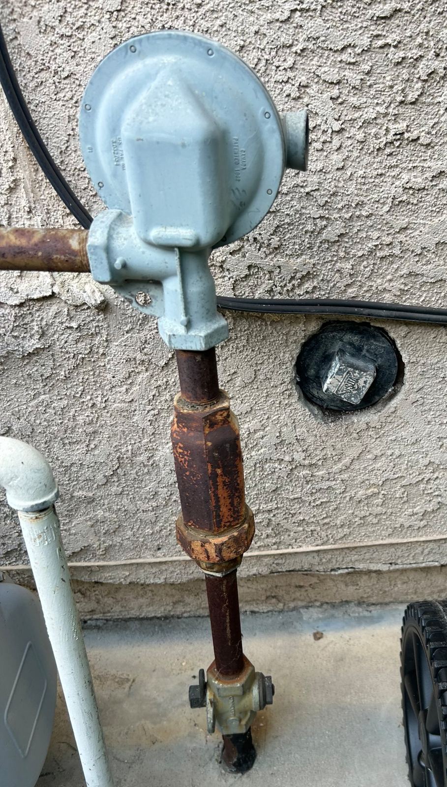 New replacement cap installed on a sewer cleanout in a stucco wall