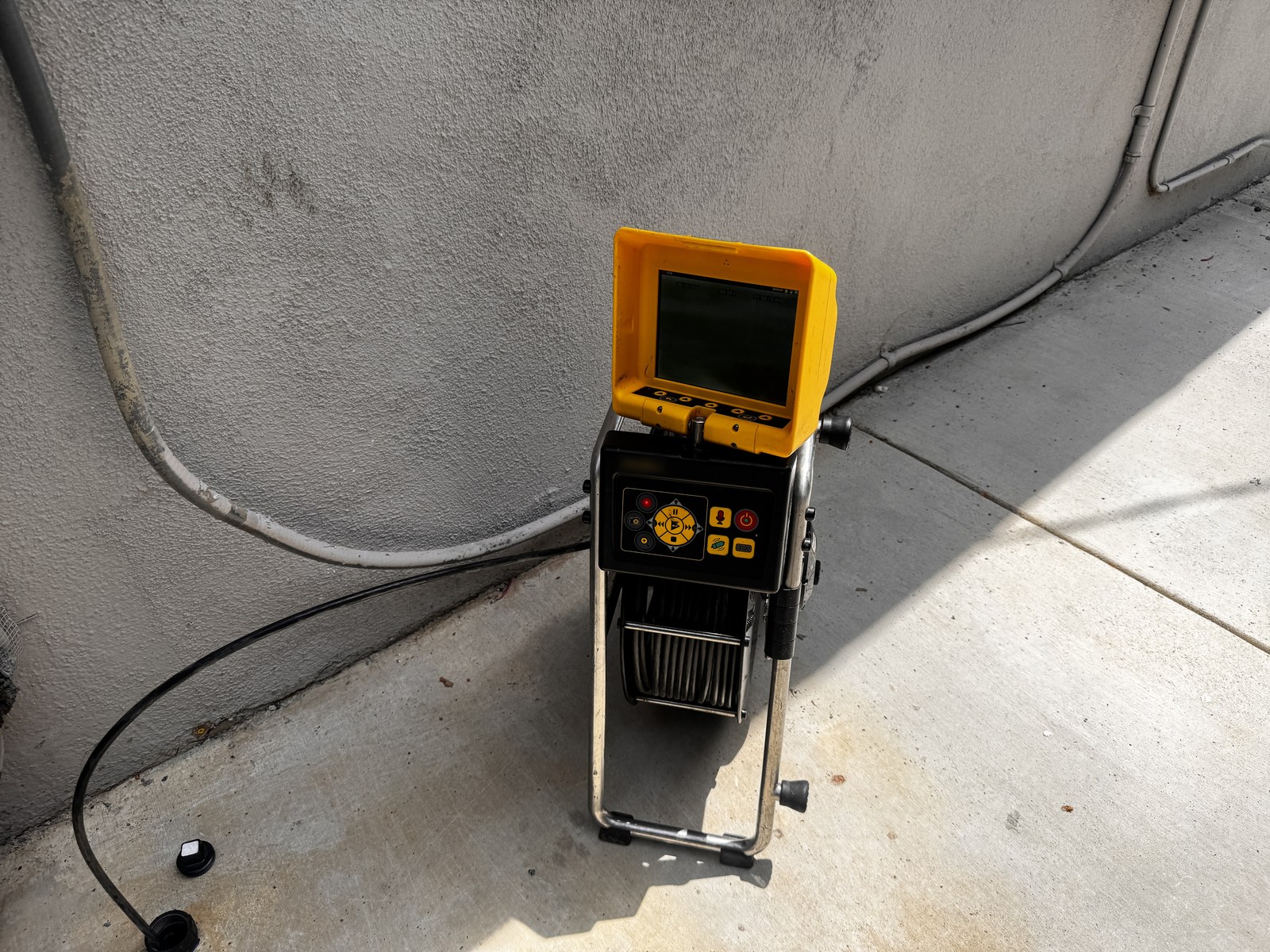 Sewer inspection camera reel and monitor set up at a ground-level cleanout access point